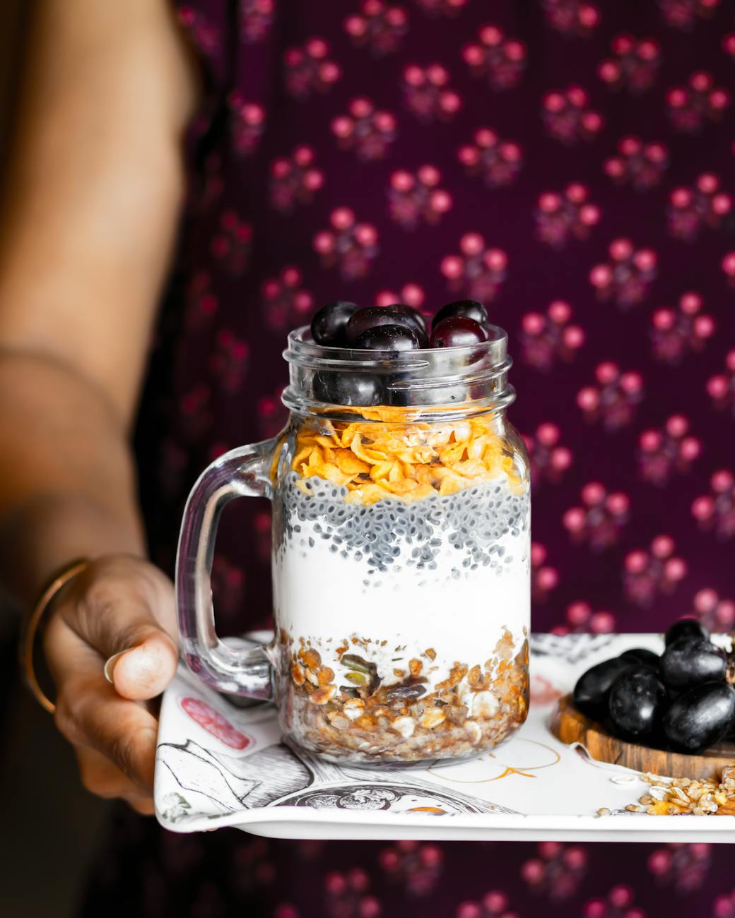 woman hand holding tray with fruit dessert in jar